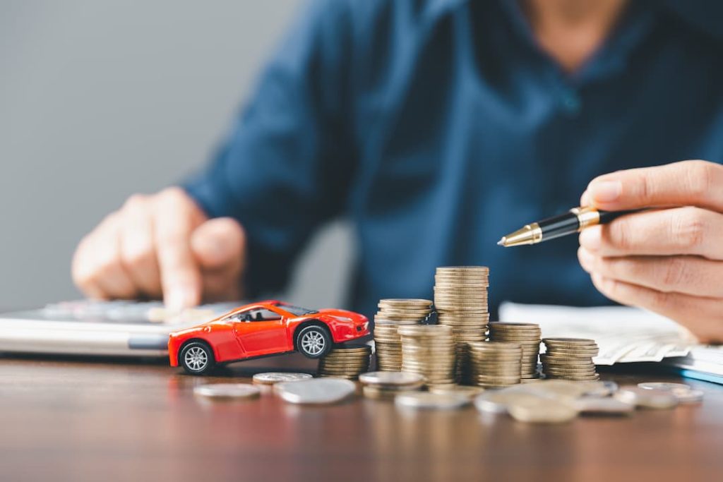 a toy car, stacks of money and a man with a calculator and pen