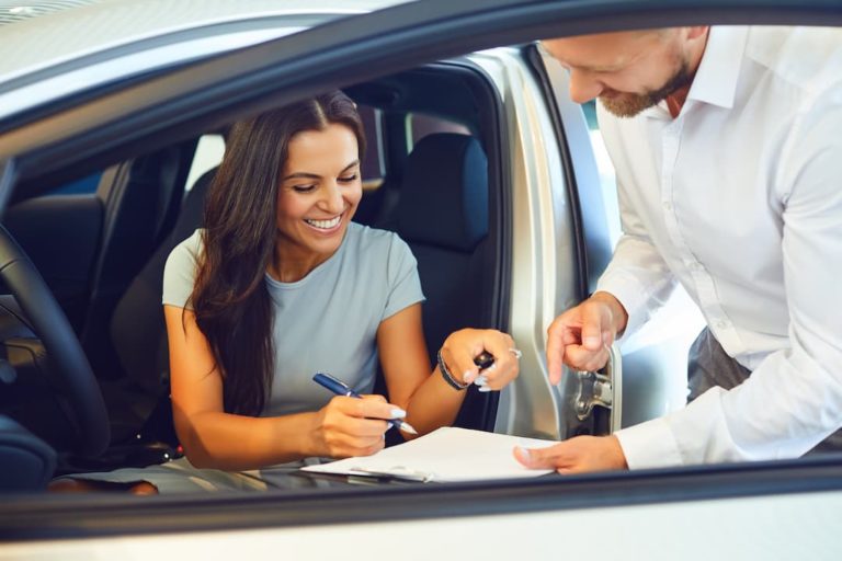 woman in a car handing over the keys and signing a document